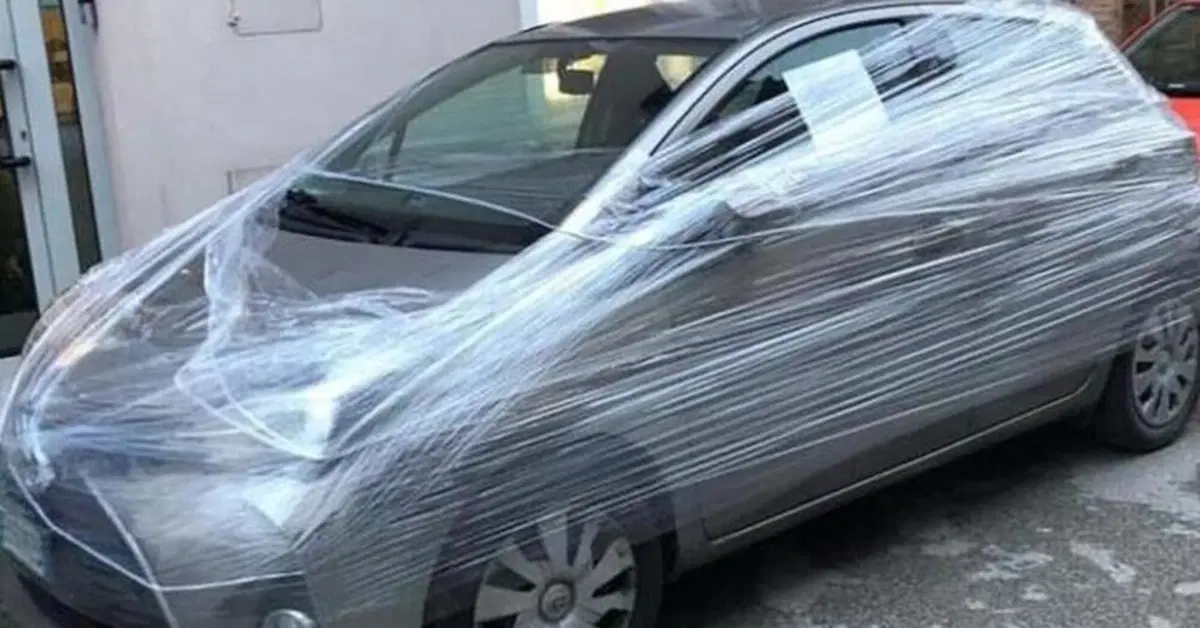 Incarta con il cellophane l'auto parcheggiata davanti al suo negozio