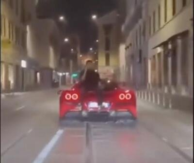 Milano &egrave; follia: seduto sul cofano di una Ferrari al telefono 