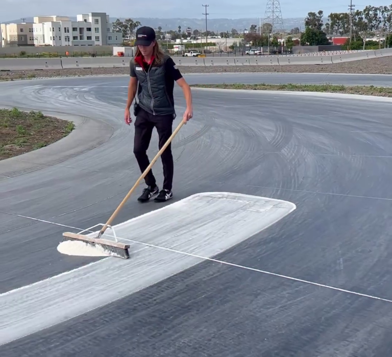 Un addetto del Porsche Experience Centre sparge la farina sulla pista